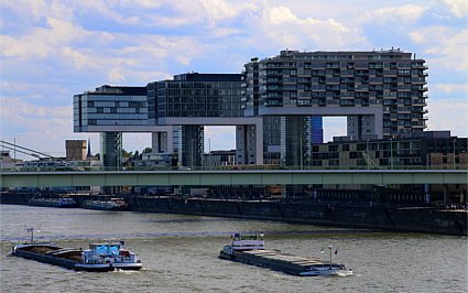 Die drei Kölner Kranhäuser am Rhein - im Vordergrund zwei Frachtschiffe